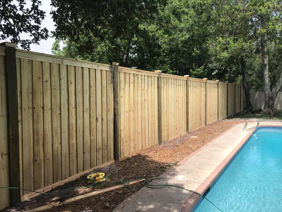 Wooden privacy fence next to a pool. Work by Gulf Freeway Landscaping and Outdoor Living